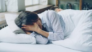 Femme stressée en pleine crise d'angoisse nocturne dans son lit