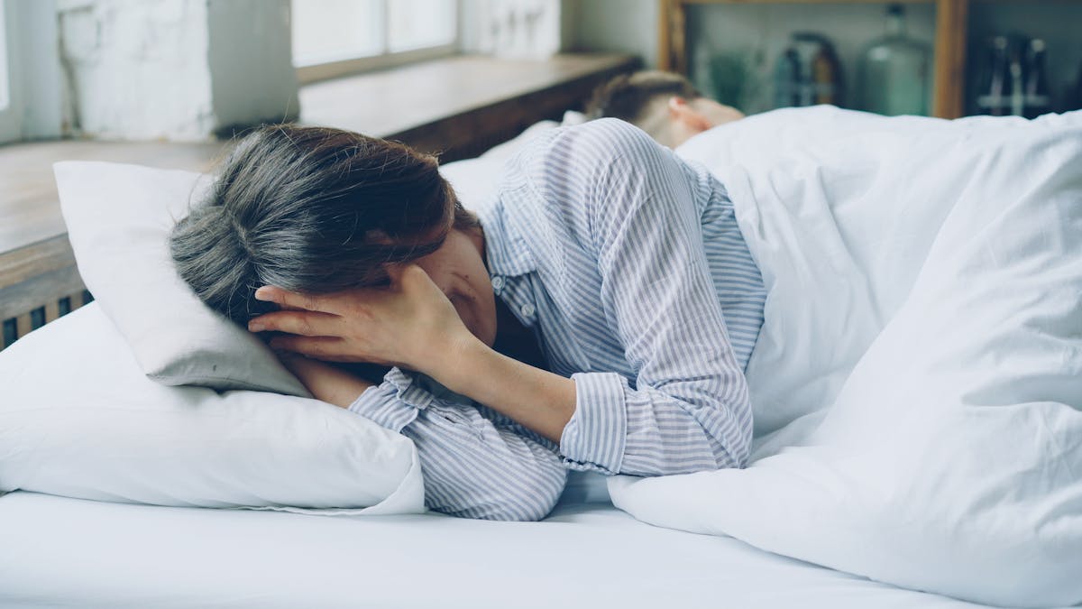 Femme stressée en pleine crise d'angoisse nocturne dans son lit