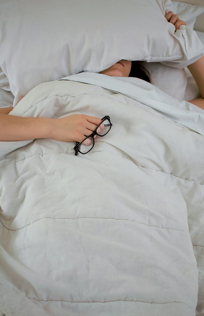 Personne épuisée se couvrant le visage avec un oreiller, signe de manque de sommeil chronique